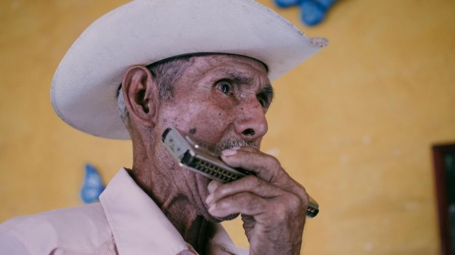 Elderly man playing a harmonica.