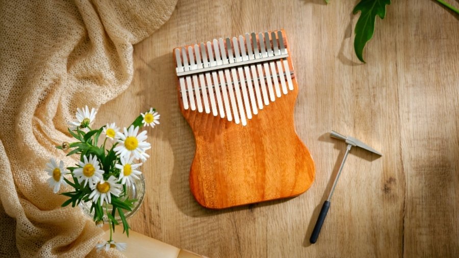 Unique wooden kalimba on a wooden table with flowers and a kalimba tuner