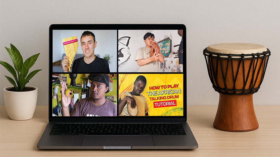 Laptop displaying music tutorial videos beside a djembe drum and plant on a wooden desk.