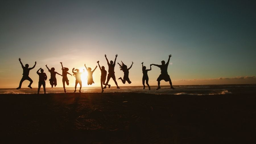 Silhouettes of people captured mid-jump against a bright background.