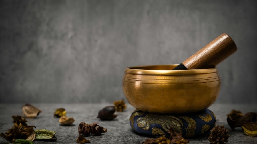 Tibetan singing bowl with a wooden mallet resting on a cushion.
