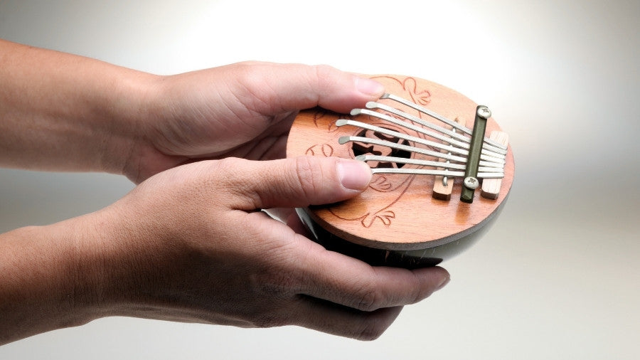 Coconut Thumb Piano Kalimba Being held in the hand to show scale