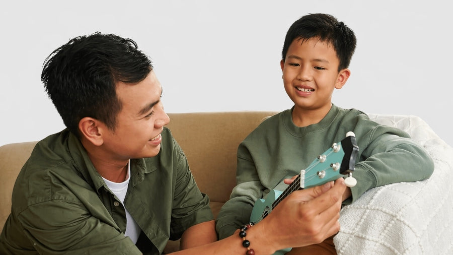 Father teaching his son to play the ukulele