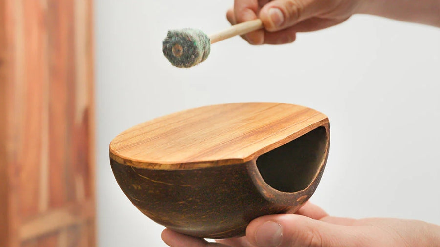 Playing the coconut shell drum with a beater