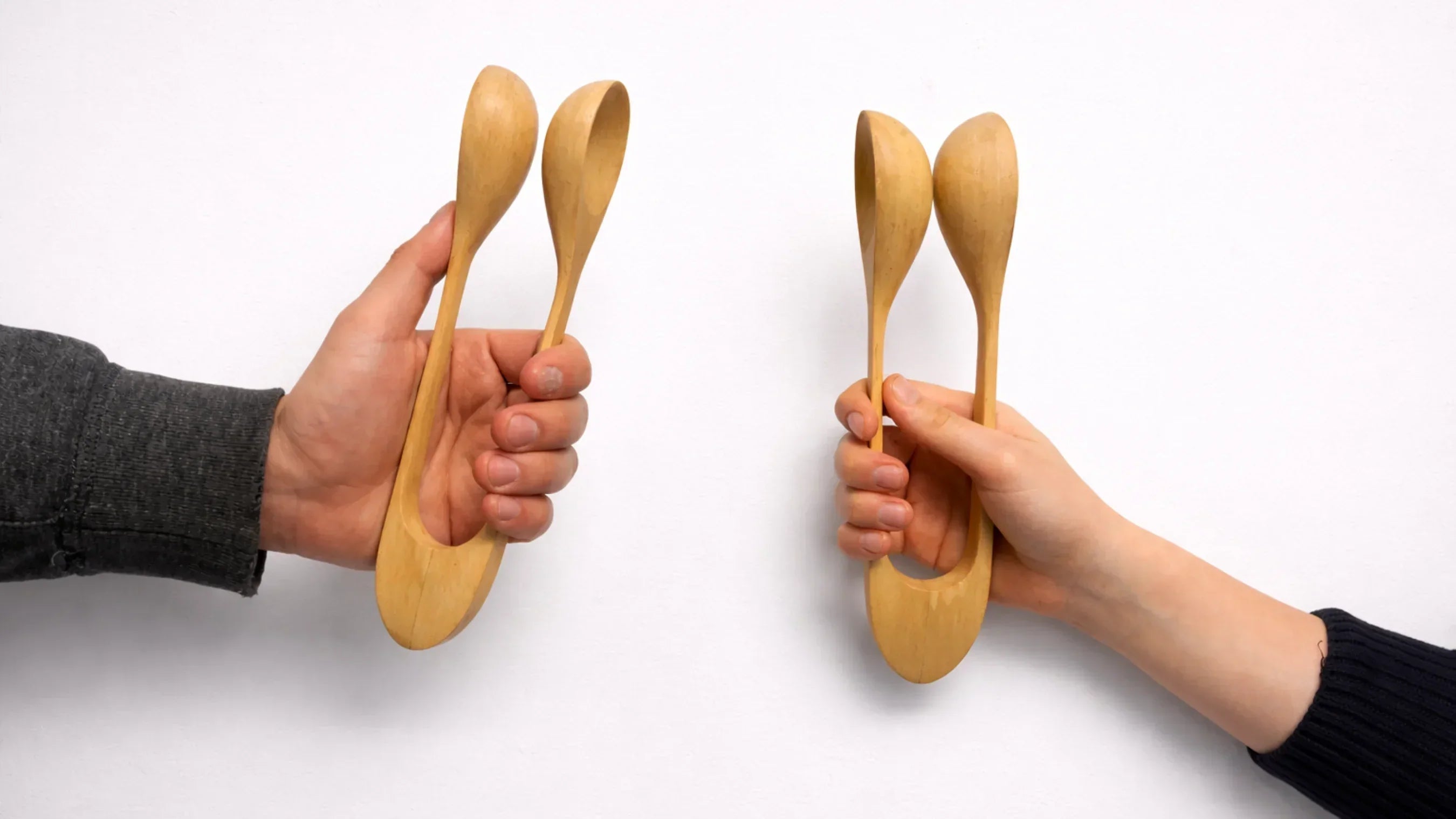 adult hand and child hand holding wooden musical spoons