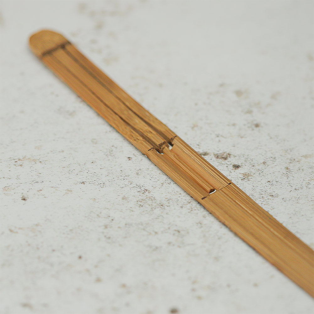 Close up of plain natural bamboo Karinding jaw harp showing the vibrating mechanism and fine details.