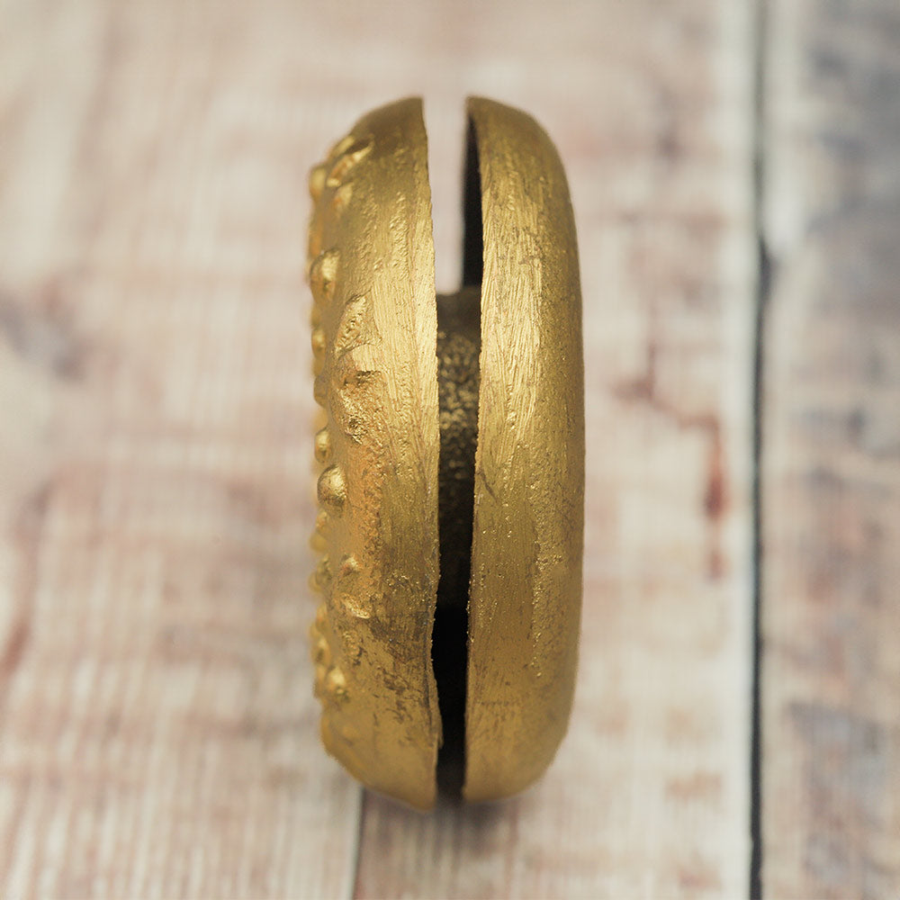 Side of the Brass Meo finger bell showing the slit in the middle, highlighting its construction.