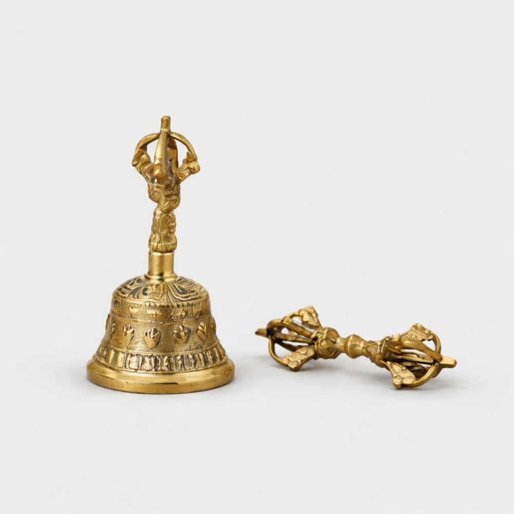 Golden brass bell and dorje striker on a white studio background