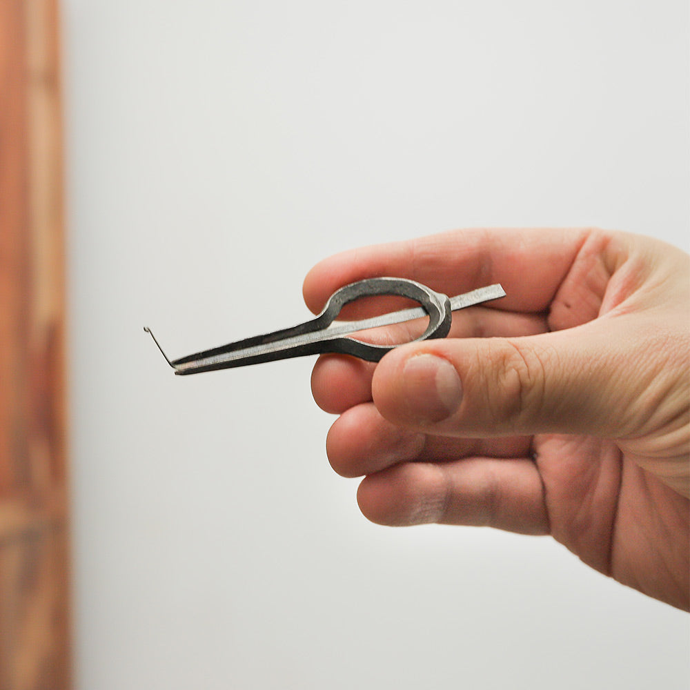 Cast iron mouth jaw harp from Nepal held in hand, showcasing its size and intricate design.