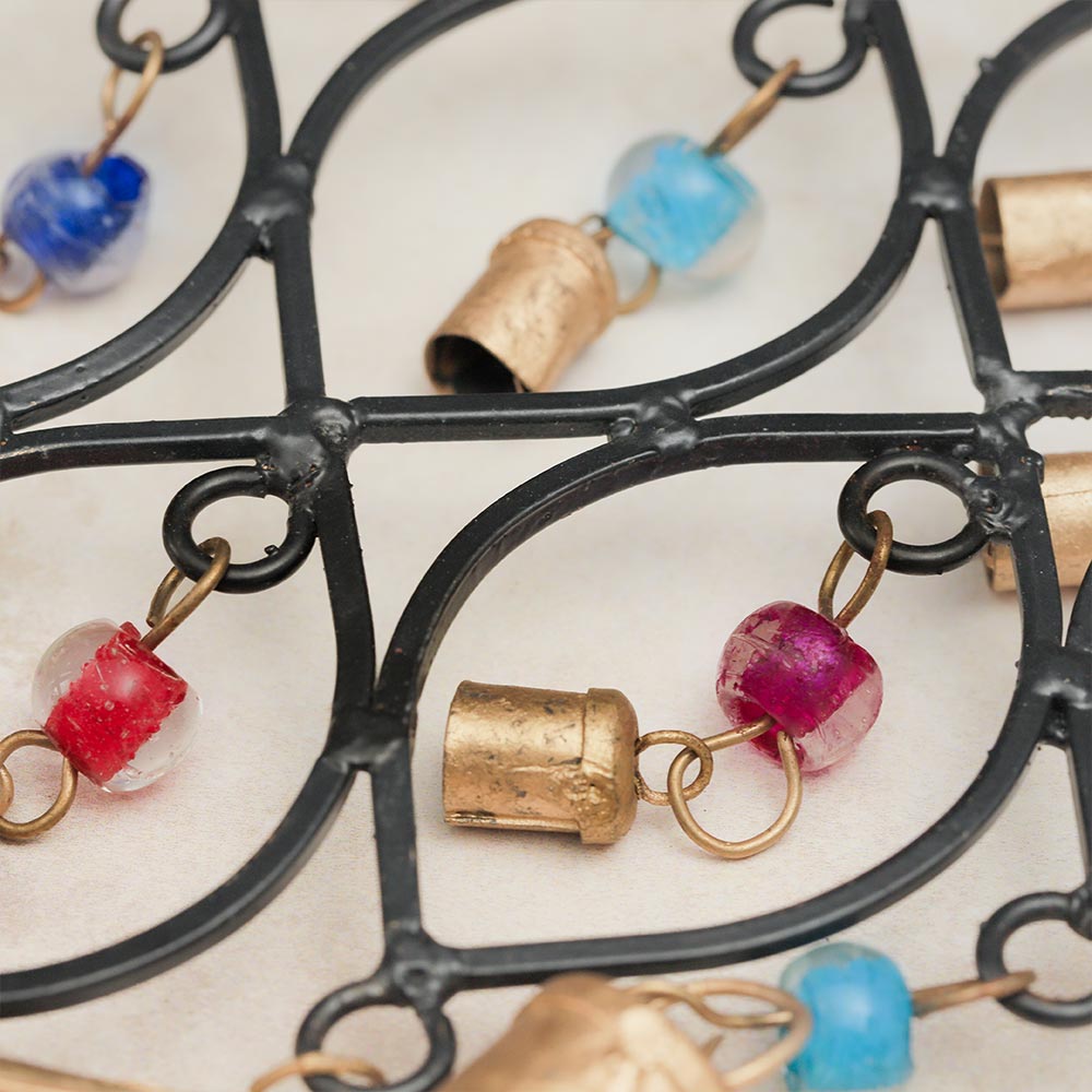 Close-up of the cast iron windchime, showcasing colorful glass beads, metal brass bells, and the metal frame.