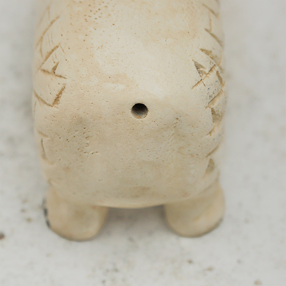 Close-up of the wooden sheep whistle back, showing the whistle mechanism and hole for sound.