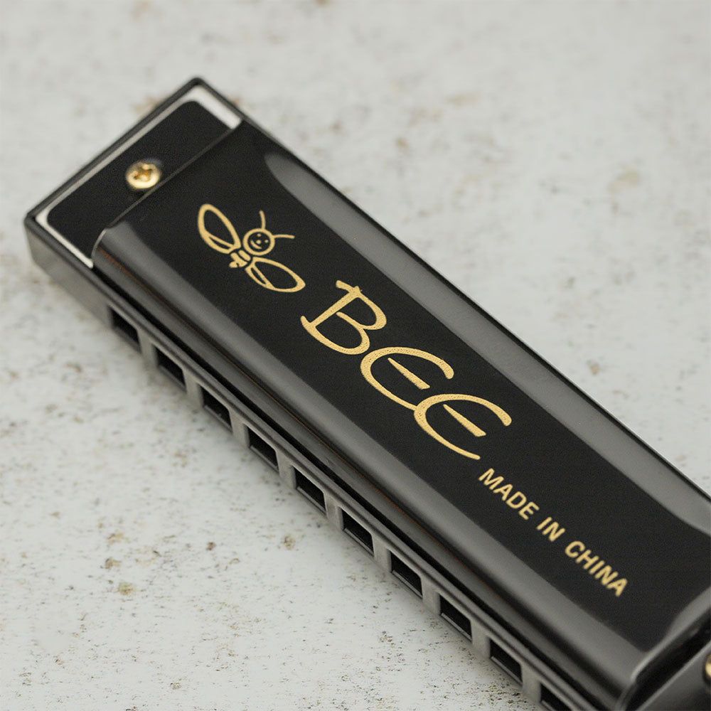 Close-up of the black Bee harmonica showing the text "BEE - Made in China."