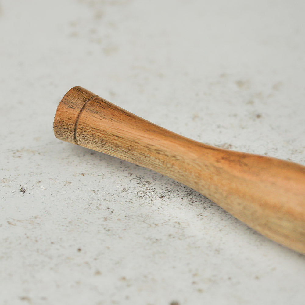 Close-up of the end of a traditional chapati rolling pin, showcasing the smooth wooden surface and shape.