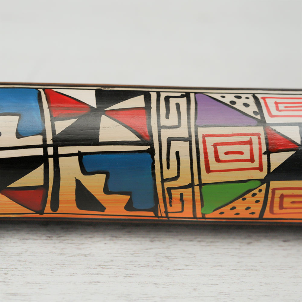 Extreme close-up of the vibrant, geometric hand-painted design on a Peruvian rainstick, highlighting the intricate colours and patterns.
