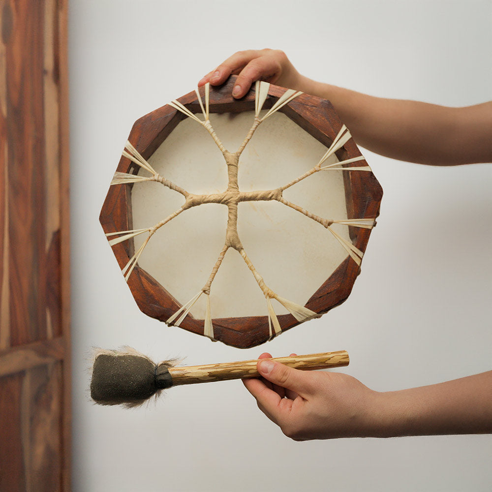 Close-up of the back of a 30cm hexagon shamanic frame drum showing rope ties, held in hand for scale with a fur beater.