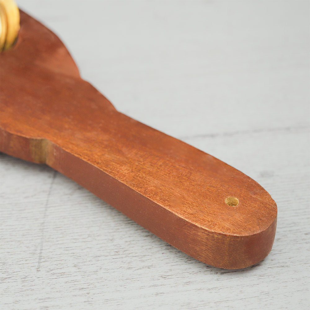 Close-up of the wooden handle of an Indian Khartal paddle shaker, highlighting its smooth texture