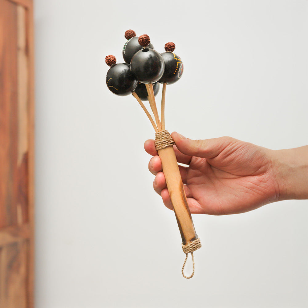 Handheld Labora shaker with a dot-painted design and bamboo handle, producing rhythmic sounds.