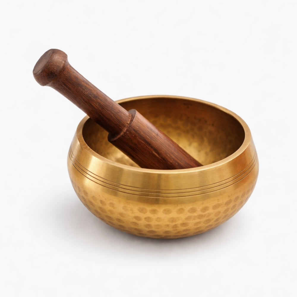 Brass singing bowl with wooden stick beater on a white studio background