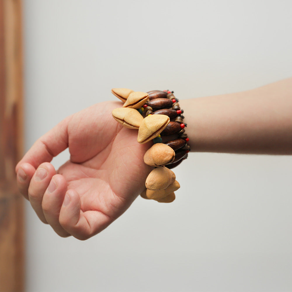 Close-up of a Lima wrist nut seed bracelet worn on the wrist with a hand in the image to show the scale.