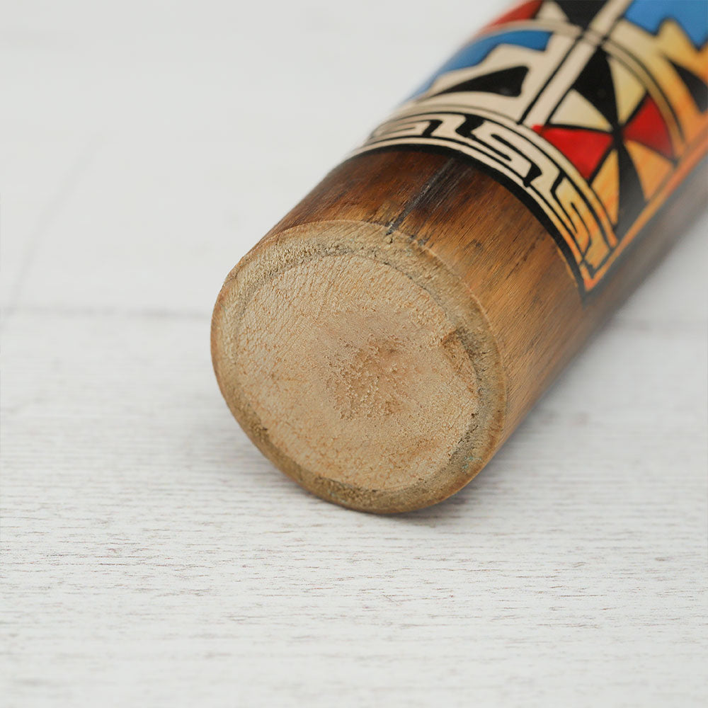 Close-up of the end of a painted Peruvian rainstick, showcasing the intricate design and details.