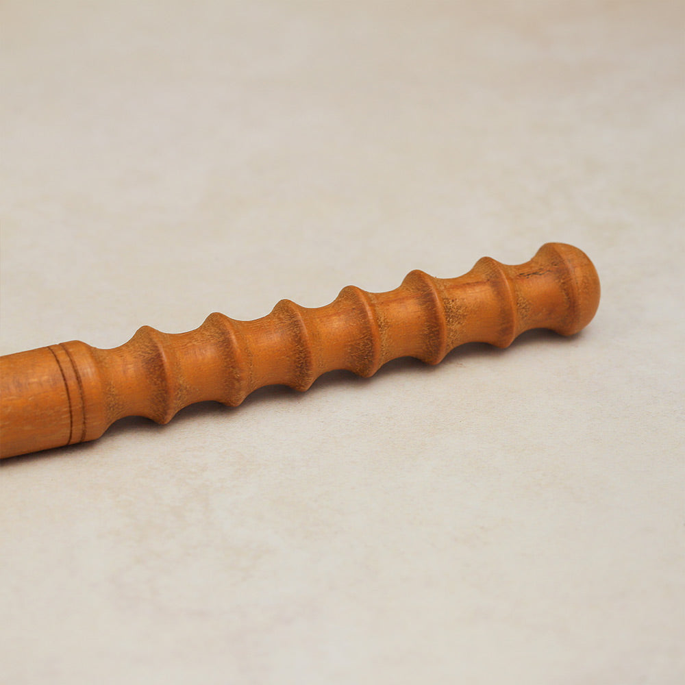 Close-up of the ridged end of the wooden Pasar Guiro, showing its textured surface.