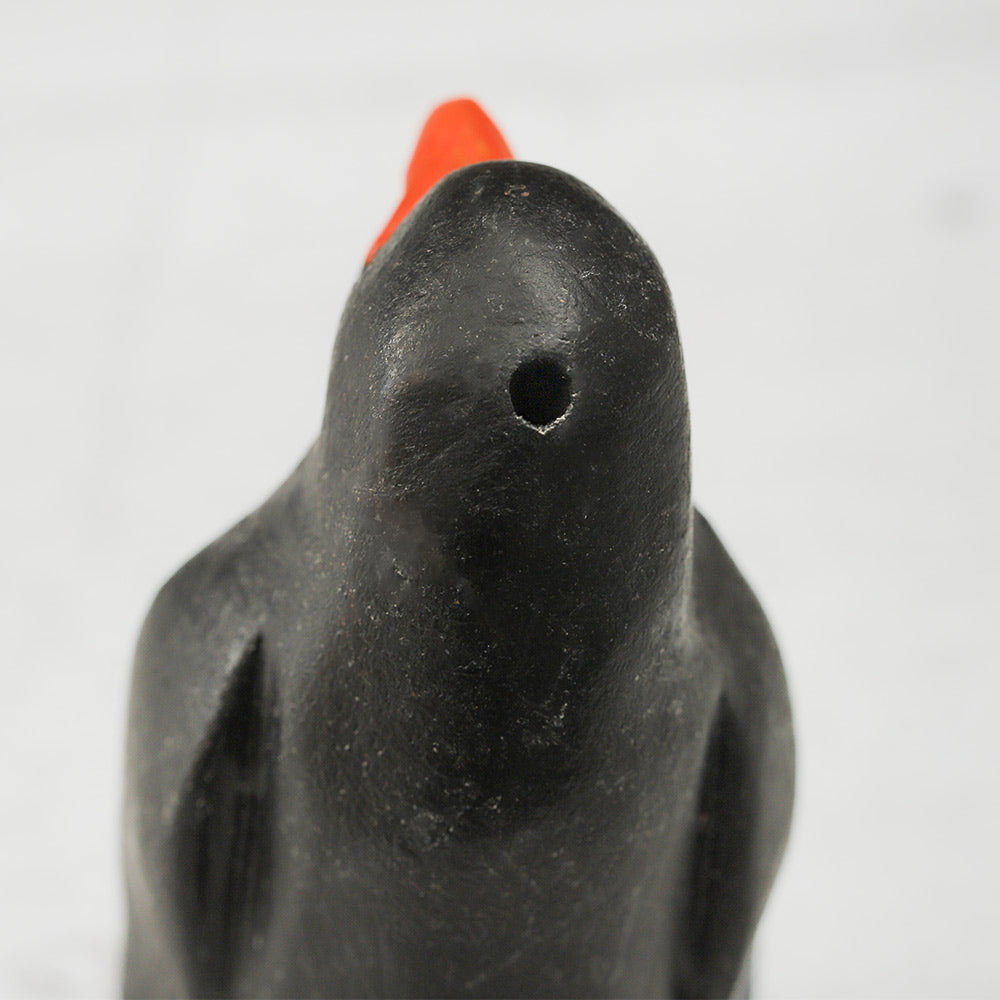 Close-up of the back of the wooden penguin ornament whistle, showing the whistle hole.