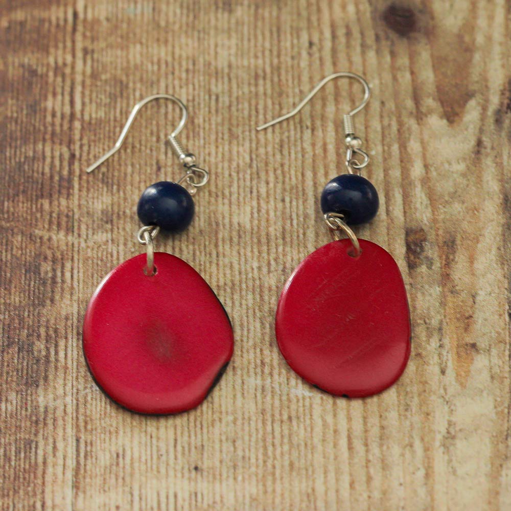 Red and blue Tagua earrings on a wooden backdrop