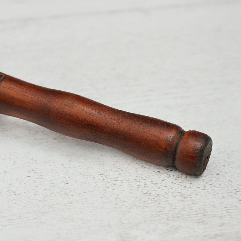 Close-up of the wooden handle of the Terre Shamanic rattle shaker, highlighting its texture and design.