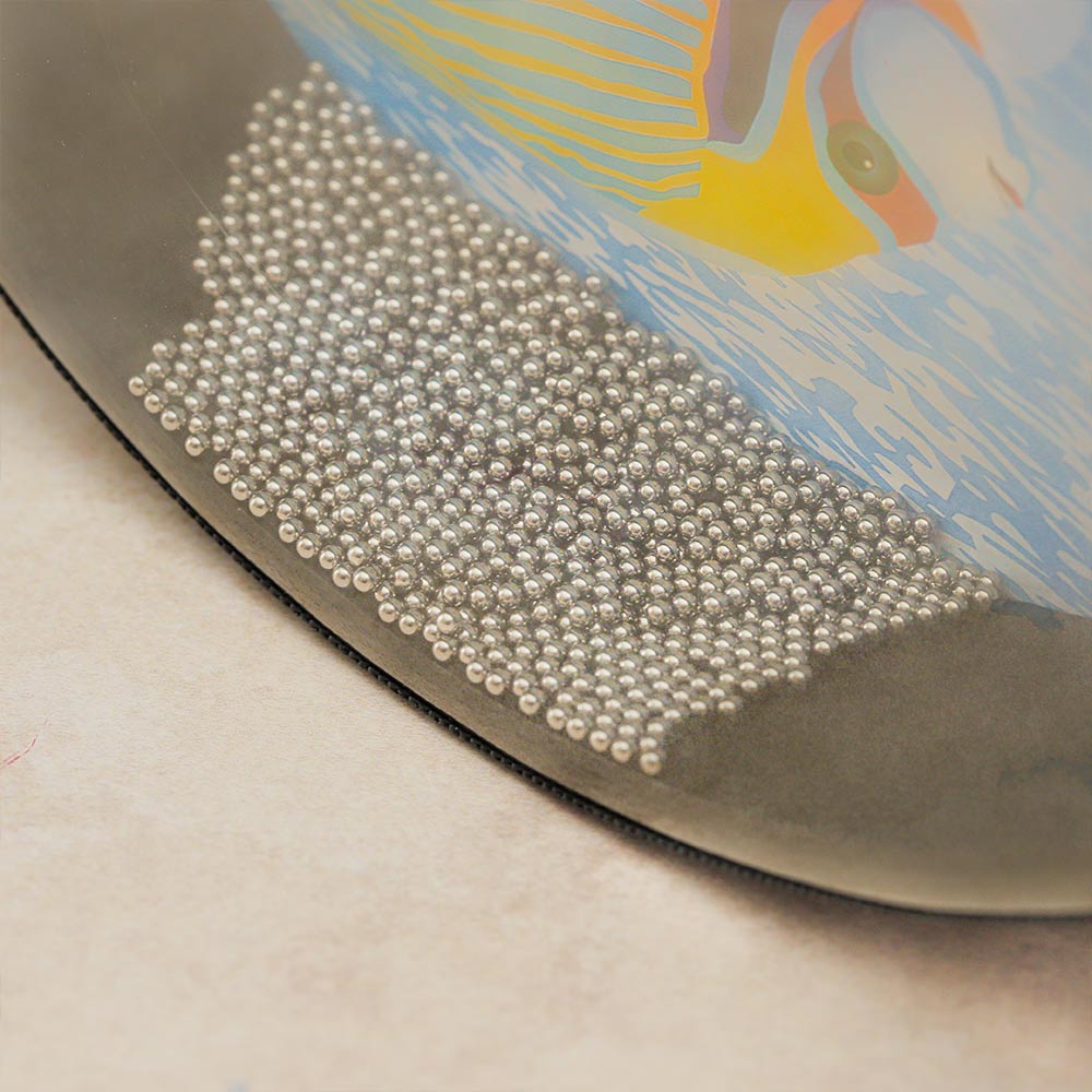 Close-up of the tropical fish drum, highlighting the small beads inside and the intricate fish design.