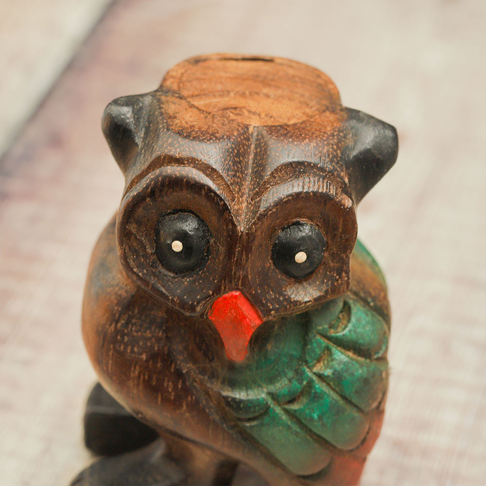 Close up of the front of the hand painted wooden hooting owl whistle showing the owl’s face.