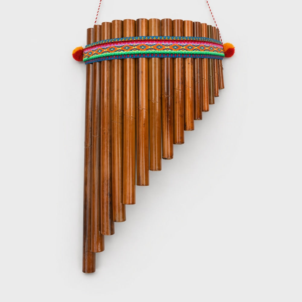 Large dark bamboo panpipes flute with colourful ribbon band on a white studio background