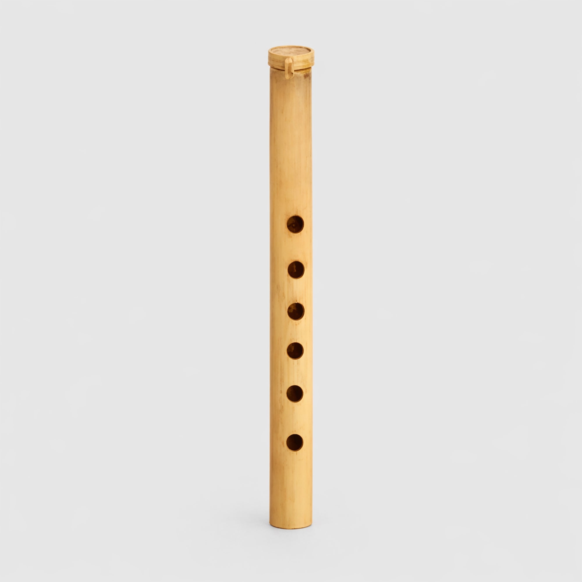 Small traditional Gamelan Suling bamboo flute from Indonesia on a light gray studio background