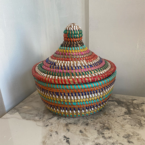 Multicolored African woven basket on a marble surface with a neutral background