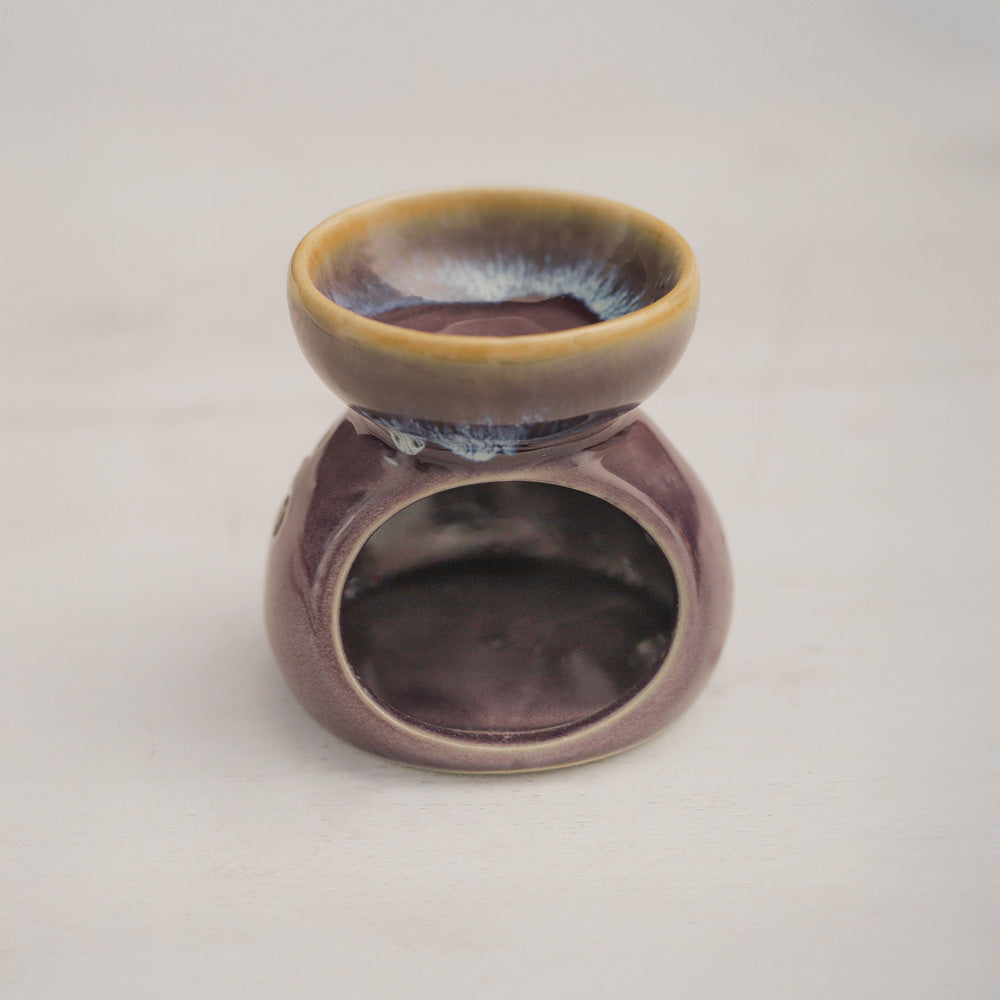 close up image of purple oil burner on orange background