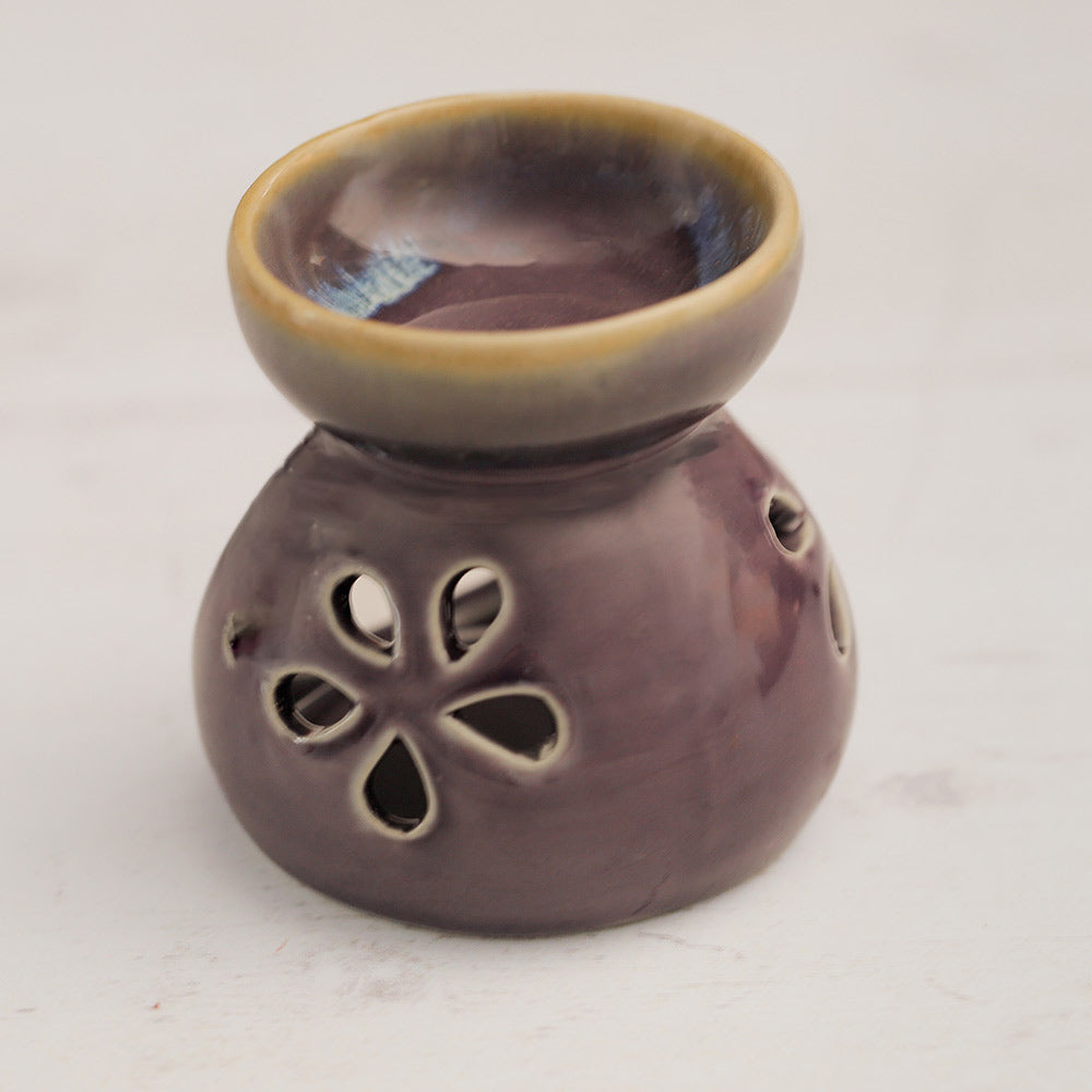 Purple ceramic oil burner with decorative design on a white background