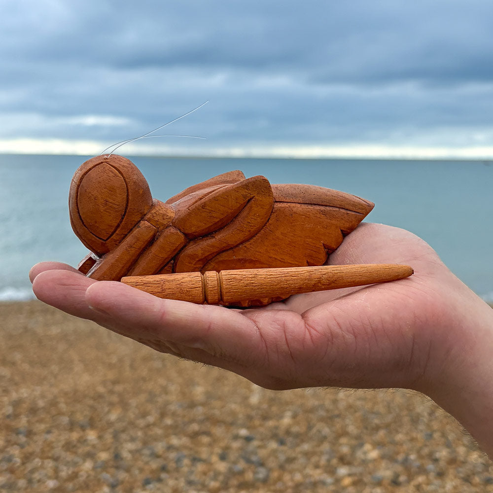 wooden cricket guiro instrument in hand with sea background