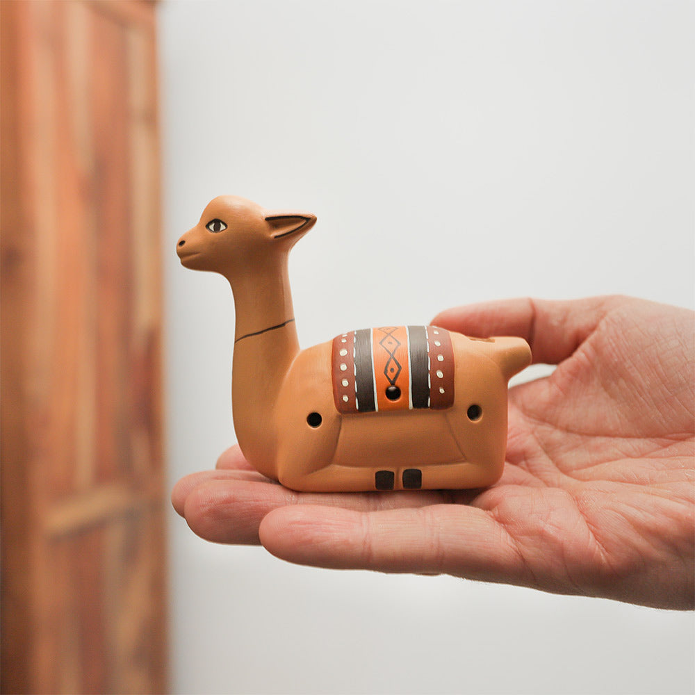 Llama clay ocarina held in hand, demonstrating its size and unique shape.