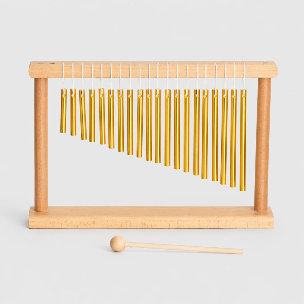 Wooden chimes with gold bars and a wooden mallet on a light gray background