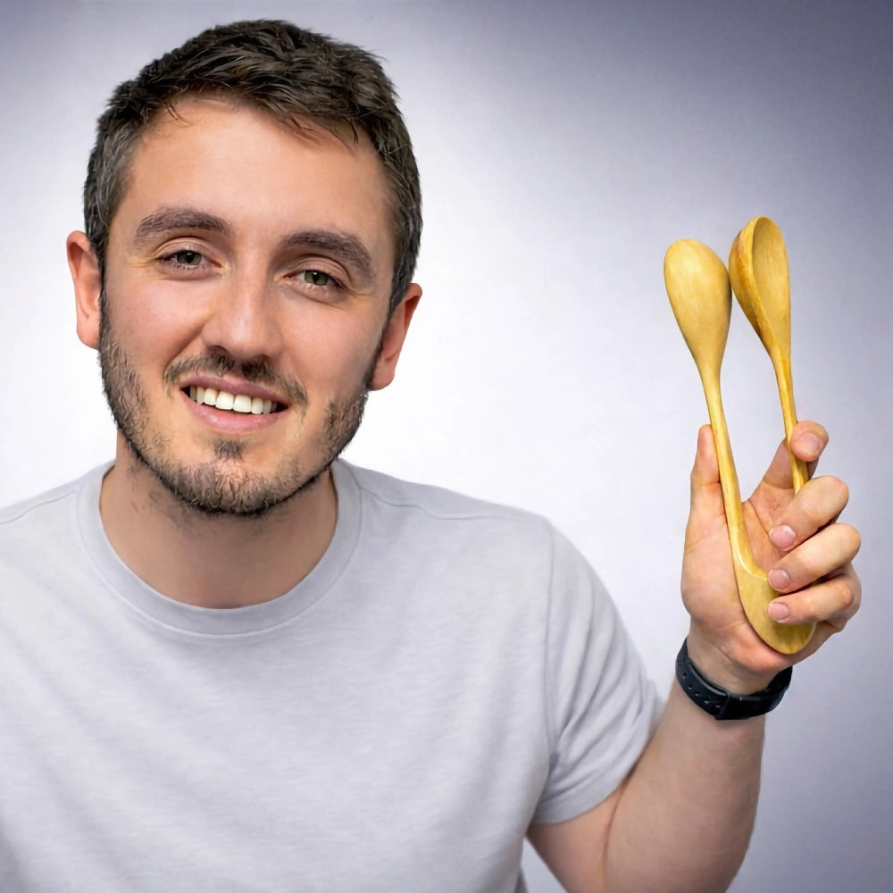 Man holding two wooden musical spoons against a plain background