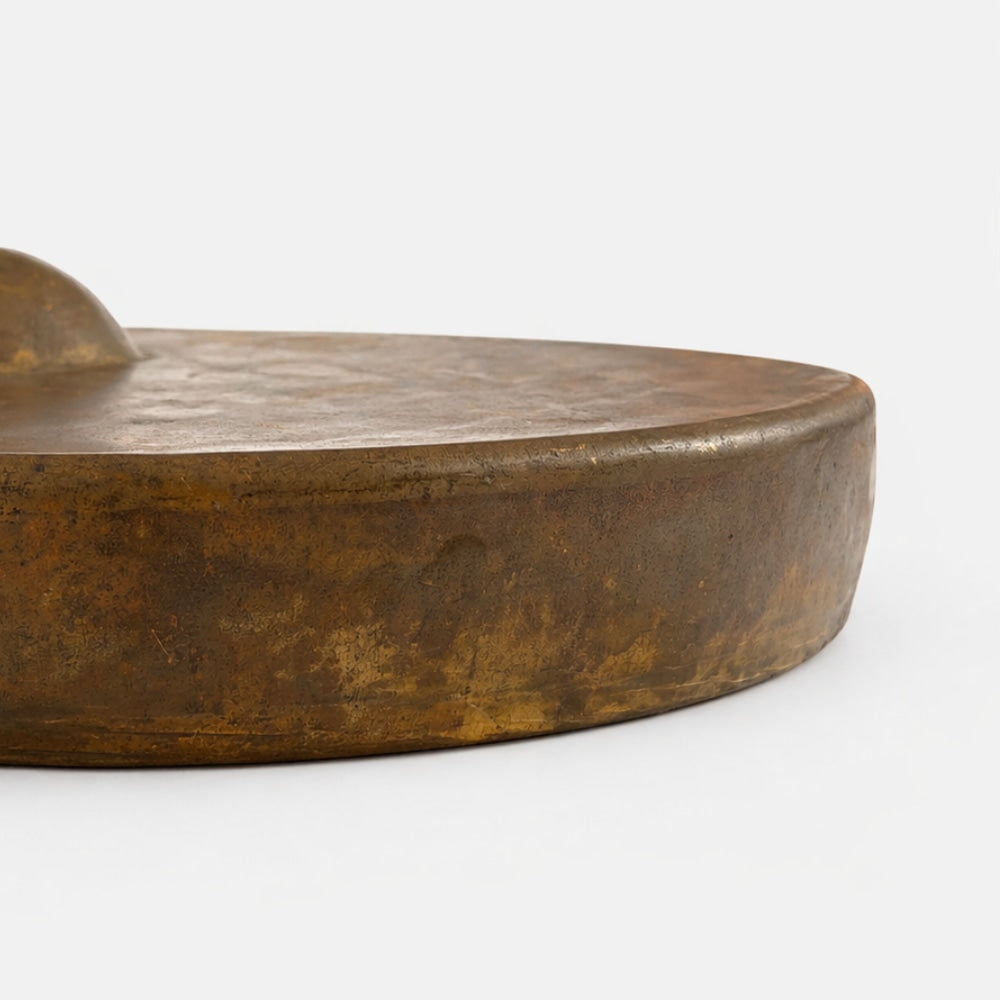 Close up of round textured gong surface showing thickness on a white studio background