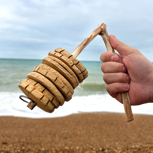 Hand holding a rakatak on a beach with ocean in the background
