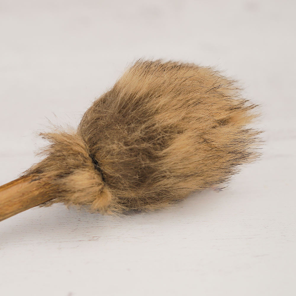 Traditional wooden beater with fur on a light gray background