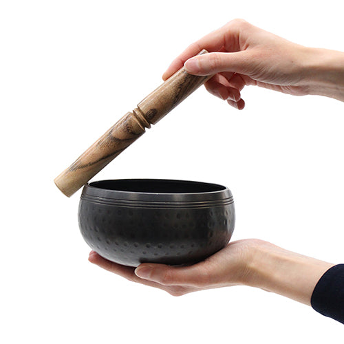 Singing bowl stick being used to play the singing bowl