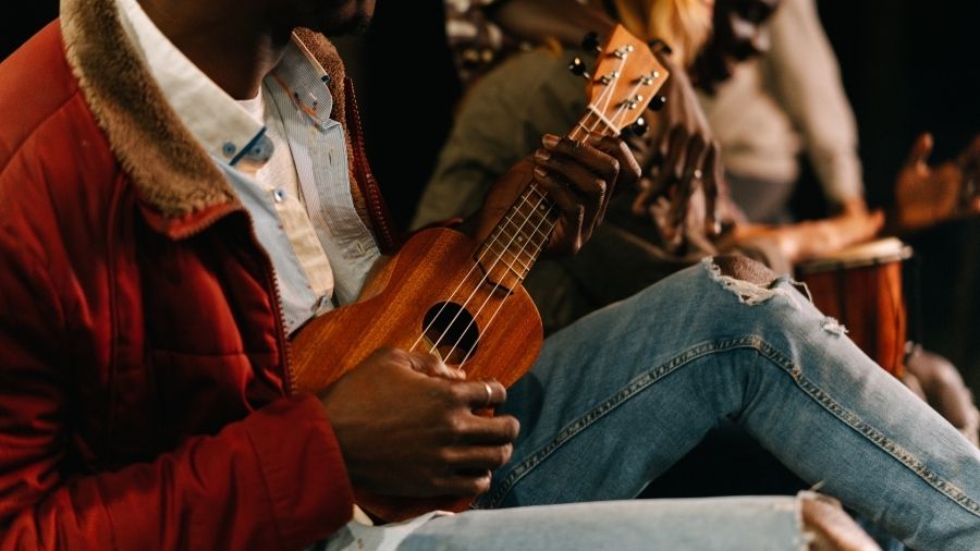 A man sitting and playing a ukulele.