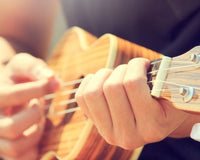 A Man Playing Ukulele on the Sandy Beach in Close up View. 