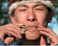 A man playing an ancient 1,700-year-old mouth harp, demonstrating that the historic instrument still produces a clear, resonant tune.