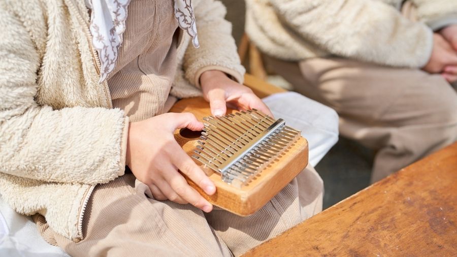 A child playing a kalimba in a warm, cozy indoor setting.
