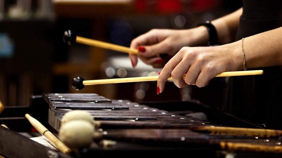 Close-up of a girl’s hands playing a glockenspiel with mallets.