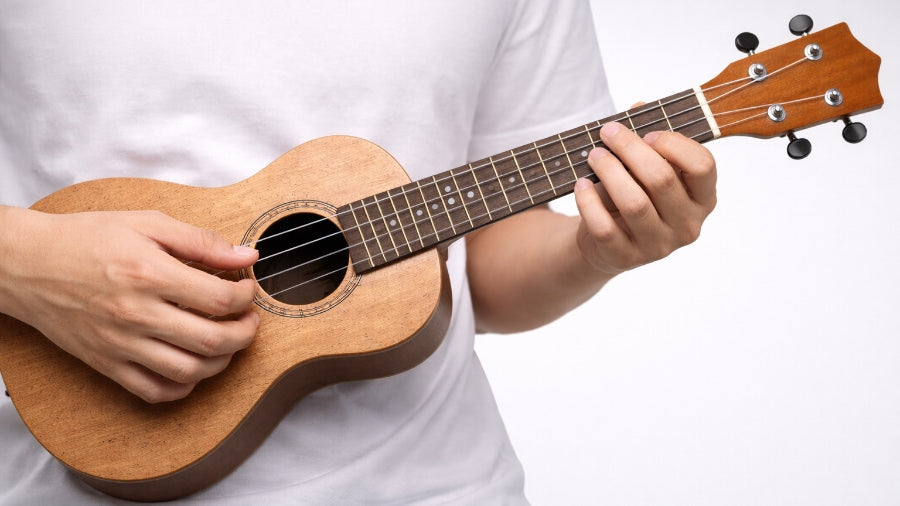Close-up of hands playing a ukulele on a clean grey studio background