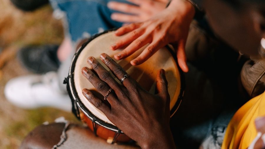 Close-up of a woman’s hands hitting a drum.